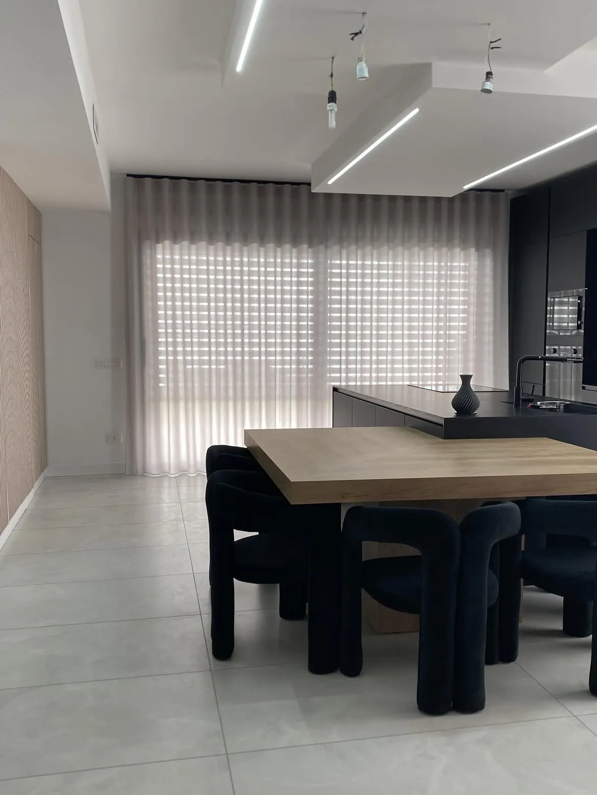 Cucina nera con tende a onda velate sulle vetrate