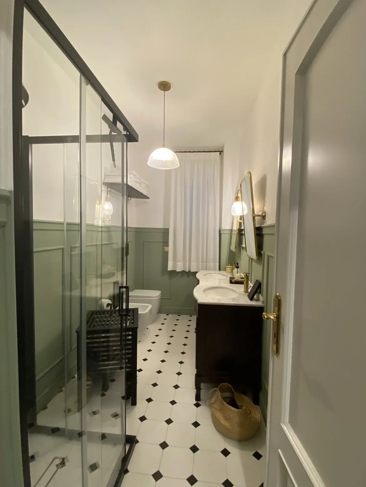 Bagno verde salvia con tenda in lino bianco, vista dalla porta